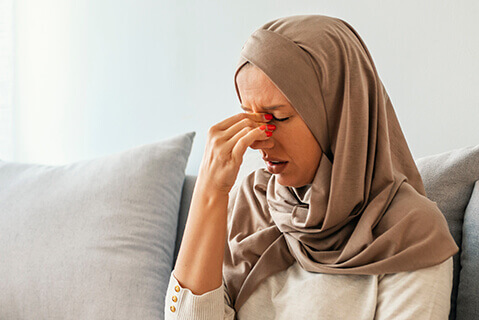 Woman holding nose with sinus pain
