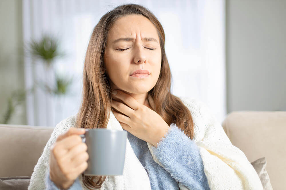 Woman holding sore throat